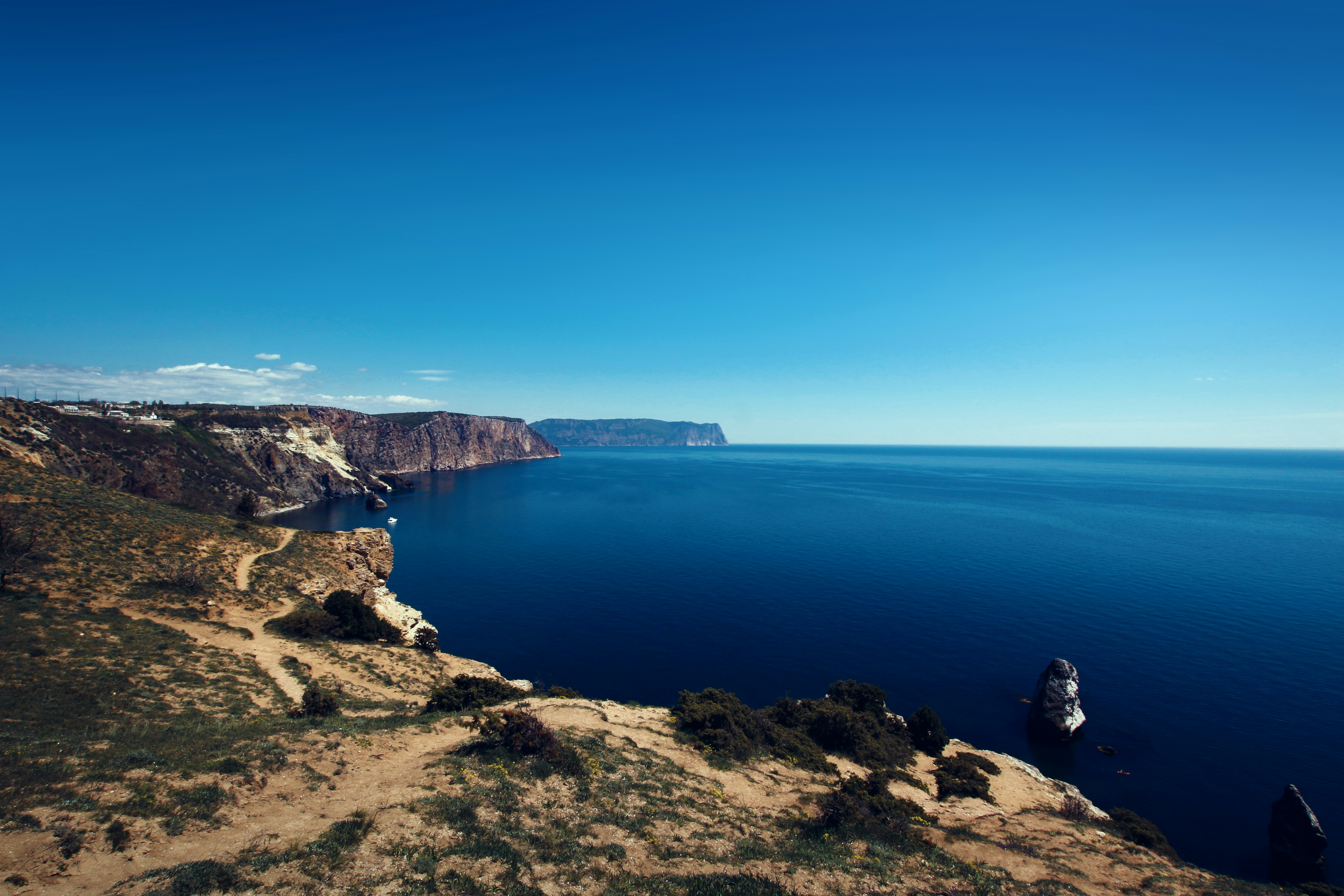 Cliffs overlook the Black Sea, stretching out beyond the horizon against a deep blue sky.