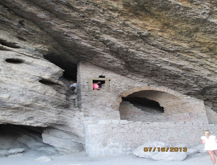 A brick archway and window built into a rock overhang.