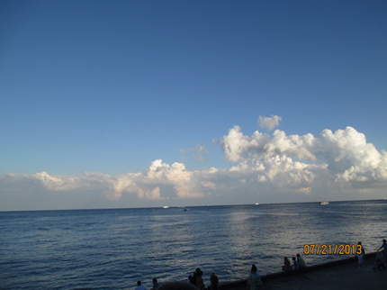 Low clouds practically touch the edge of the water in a view of the Black Sea. People gather at the shore.