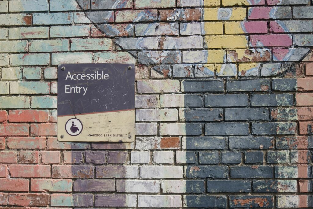 A painted brick wall with a metal sign on it from the Chicago Park District that reads, "ACCESSIBLE ENTRY."